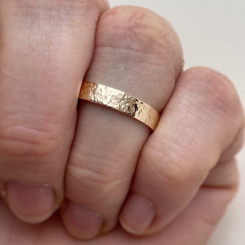 May include: A gold band ring with a hammered texture.