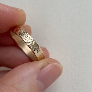 May include: A gold band ring with a hammered texture.