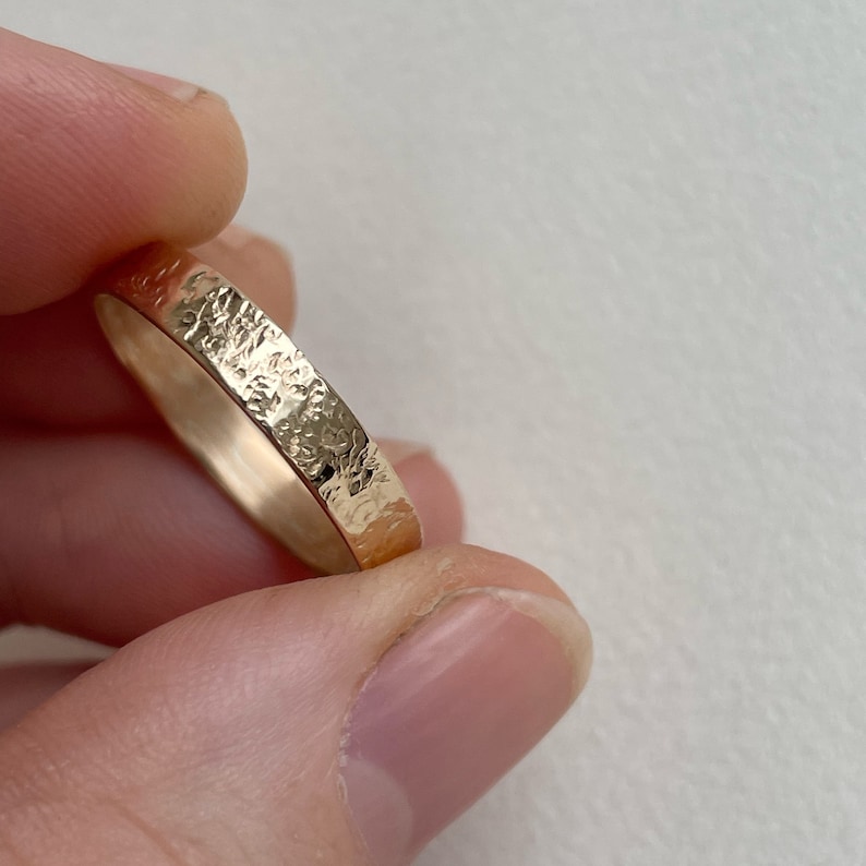 May include: A gold band ring with a hammered texture.