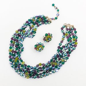 May include: A multi-strand necklace and matching earrings made of iridescent green, purple, and yellow glass beads.
