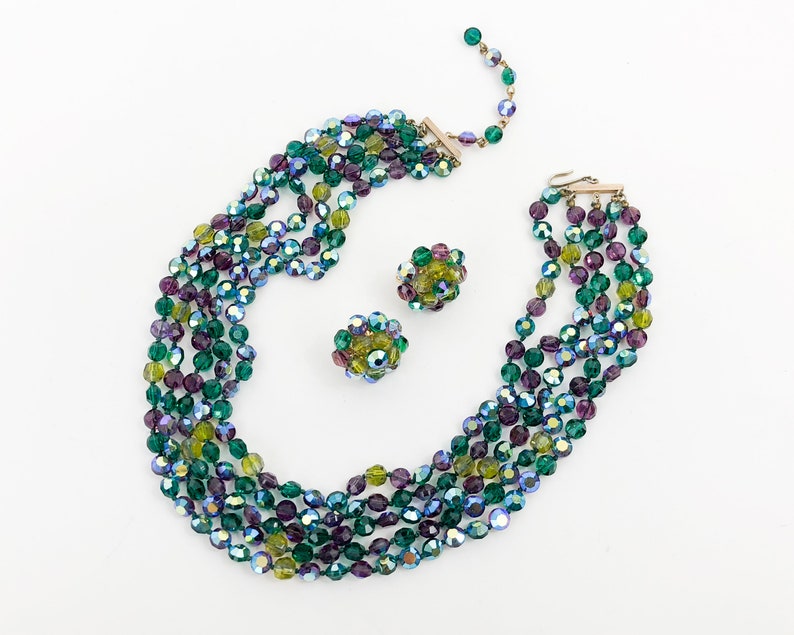 May include: A multi-strand necklace and matching earrings made of iridescent green, purple, and yellow glass beads.