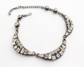 Peut inclure: Un collier en argent avec un motif de croissant de lune, orné d'un groupe de strass transparents.