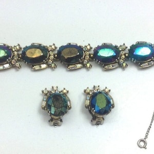 May include: A vintage iridescent blue and green glass stone bracelet and matching earrings set. The bracelet has a chain closure and the earrings are clip-on.