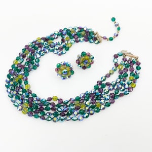 May include: A multi-strand necklace and matching earrings made of iridescent green, purple, and yellow glass beads. The necklace is layered and the earrings are cluster style.