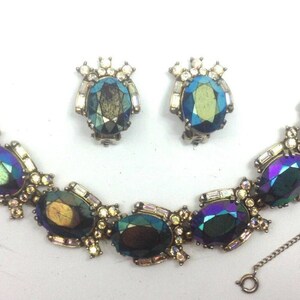 May include: A vintage iridescent blue and green glass stone bracelet and matching earrings set. The bracelet has a chain closure and the earrings are clip-on.