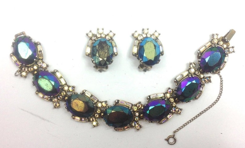 May include: A vintage iridescent blue and green glass stone bracelet and matching earrings set. The bracelet has a chain closure and the earrings are clip-on.