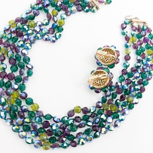 May include: A multi-strand necklace and matching earrings made of green, purple, and blue iridescent glass beads.
