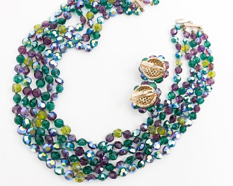 May include: A multi-strand necklace and matching earrings made of green, purple, and blue iridescent glass beads.