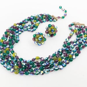 May include: A multi-strand necklace and matching earrings made of iridescent green, blue, and purple glass beads. The necklace is made of five strands of beads and the earrings are made of clusters of beads.