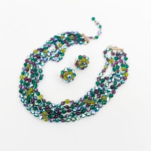 May include: A multi-strand necklace and matching earrings made of iridescent green, purple, and yellow glass beads.