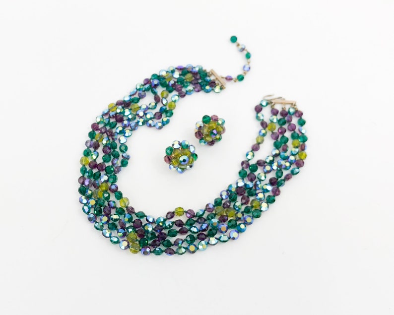 May include: A multi-strand necklace and matching earrings made of iridescent green, purple, and yellow glass beads.