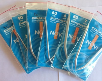 May include: Five packages of circular knitting needles in various sizes. The needles are silver and the packages are blue with white text. The text on the packages reads "RUNDPINNE" and includes the size of the needles in centimeters and millimeters.