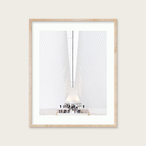 May include: A photograph of the interior of a large, modern building with a white, geometric ceiling. The ceiling is made up of many angled panels that create a sense of depth and perspective. There are people standing on a platform in the center of the room, looking up at the ceiling.