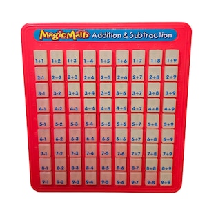 May include: A red educational toy labeled "Magic Math Addition & Subtraction." The toy features a grid of white blocks with addition and subtraction problems. The top of the toy has the "Magic Math" logo in blue and yellow.