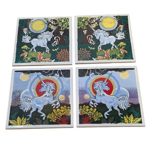 May include: Set of four square ceramic coasters. Each coaster features a whimsical illustration of a white unicorn with a spiraled horn, set against a backdrop of a full moon, trees, and foliage. The color palette includes blues, greens, and yellows.