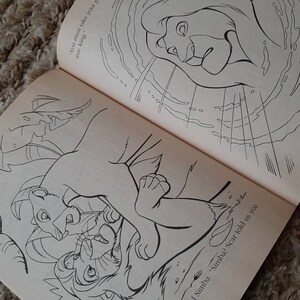 May include: Black and white illustration of a lion cub being held by a larger lion. The text "You must take your place, Simba. You are the true king." is visible in the background.