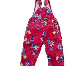 May include: Red corduroy overalls with a colorful star pattern. The overalls have adjustable straps, a bib pocket, and the OshKosh logo. The star pattern includes blue, green, and yellow stars. A vintage children's garment.
