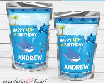 May include: Two blue and silver juice pouches with a shark theme. The pouches have a blue background with white waves and a palm tree. The text "Happy 4th Birthday" is in yellow with a star. The name "Andrew" is in red. The pouches have a shark with a toothy grin and the text "Here comes the teeth!"