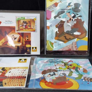 May include: Four collectible Disney postage stamp sheets encased in clear plastic protectors. The stamps feature colorful illustrations of Mickey Mouse and Goofy in various scenes, with text including Walt Disney, Grenada, and character names.