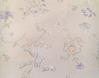 Puede incluir: Un fondo beige con un patrón repetido de diseños florales grises y marrones. El patrón presenta flores, hojas y enredaderas estilizadas.