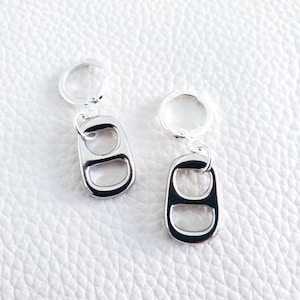 May include: A pair of silver earrings with a pull tab design. The earrings are made from recycled materials and are a unique and stylish accessory.