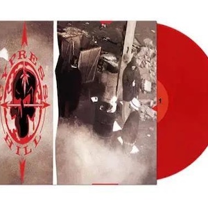 May include: A red vinyl record next to a record sleeve. The sleeve features the text "CYPRESS HILL" in a red and white design with a skull and arrows. The background of the sleeve is a sepia tone with a black and white image.