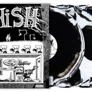 May include: A Phish vinyl record set featuring a square album cover with black and white line art of a room scene and the text PHISH. Three circular vinyl records are displayed, each with a marbled black and white pattern on the surface.