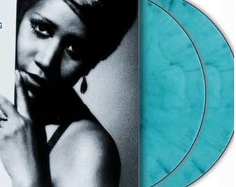 May include: A black and white photo of a woman with a turquoise blue vinyl record. The record is a double LP.
