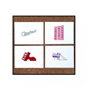 May include: Four white cards with different designs on a corkboard background. The top left card has the word "Cleveland" in blue cursive writing. The top right card has three pink silos with the words "Cocoa", "Milk", and "Sugar" written on them. The bottom left card has a red stamp with the word "EKEE" written on it. The bottom right card has a light purple building with a slide coming out of it.