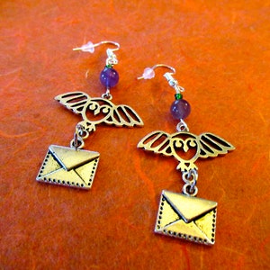 May include: Silver owl and envelope dangle earrings with purple and green gemstone accents.