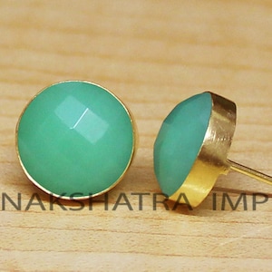 Può includere: Un paio di orecchini con pietra preziosa verde e montatura dorata. Gli orecchini sono a lobo e hanno una forma rotonda.