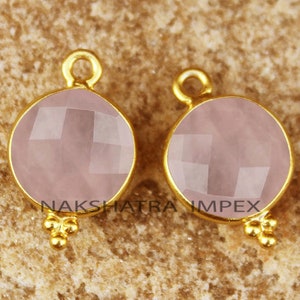 May include: Two gold-plated rose quartz pendant charms with a faceted round shape and three small gold beads at the bottom.