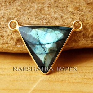 May include: Gold-tone triangle pendant with a blue labradorite gemstone. The pendant has two loops for attaching a chain or cord.