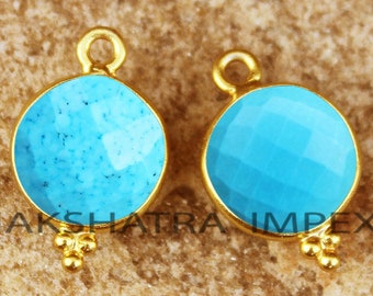 May include: Two gold-tone pendant charms with turquoise blue round cabochon stones. Each charm has a loop at the top for attaching to a necklace or bracelet.