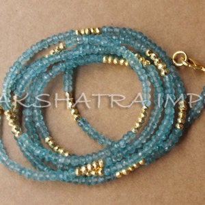 Puede incluir: Un collar de m&uacute;ltiples hilos hecho de cuentas de color azul claro y dorado. El collar est&aacute; hecho de m&uacute;ltiples hilos de cuentas peque&ntilde;as y redondas, algunas de las cuales son doradas y otras de color azul claro. El collar est&aacute; unido por un cierre dorado.