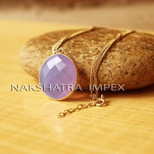 May include: A gold chain necklace with a lavender gemstone pendant. The pendant is faceted and has a round shape.