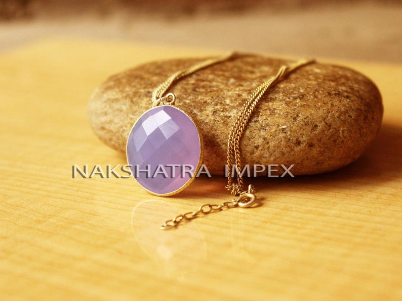 May include: A gold chain necklace with a lavender gemstone pendant. The pendant is faceted and has a round shape.
