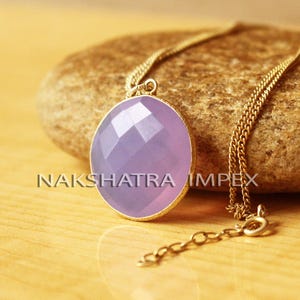 May include: A gold chain necklace with a light purple gemstone pendant. The pendant is faceted and has a round shape.