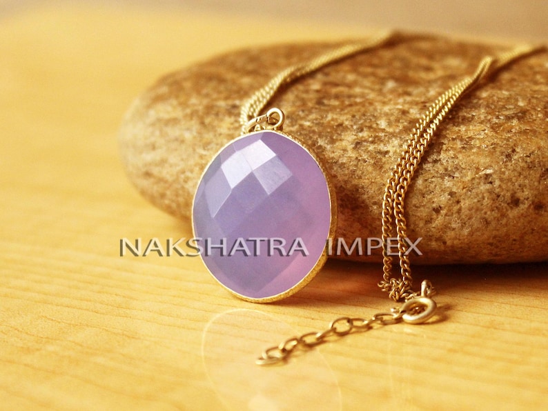 May include: A gold chain necklace with a light purple gemstone pendant. The pendant is faceted and has a round shape.