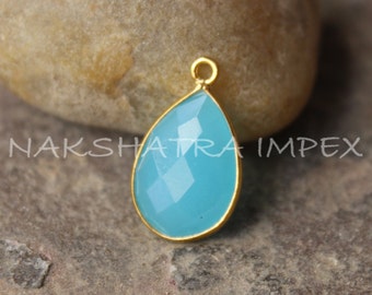 May include: A teardrop-shaped pendant with a light blue gemstone set in a gold-toned metal frame.