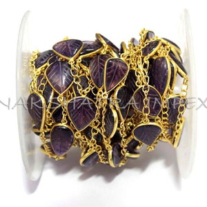 May include: A gold chain with purple leaf-shaped gemstone beads. The chain is coiled and ready to be used for jewelry making.
