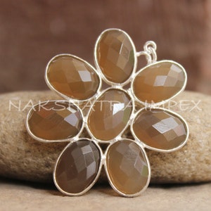 May include: A silver pendant with a flower design made of eight brown faceted stones.