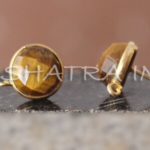 May include: A pair of gold-tone earring findings with tiger's eye stones. The findings have a loop on one side and a post on the other.
