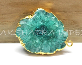 May include: A teal green agate slice with gold-plated edges and a gold loop for hanging. The agate has a natural crystal formation.