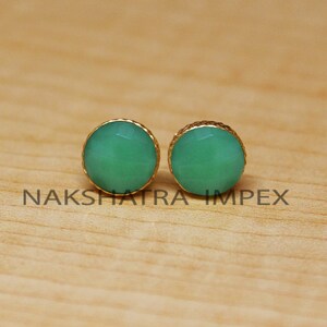 May include: A pair of gold-toned stud earrings with round green gemstone accents.