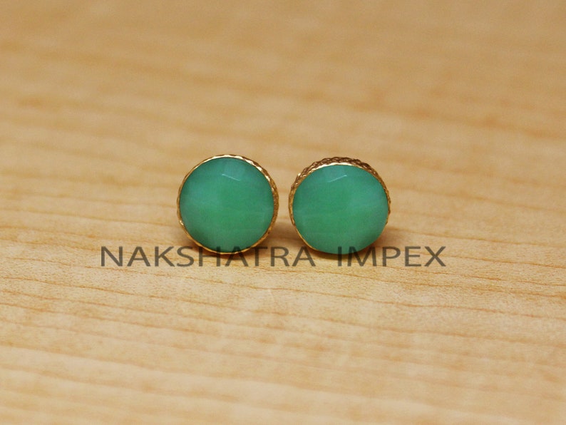 May include: A pair of gold-toned stud earrings with round green gemstone accents.