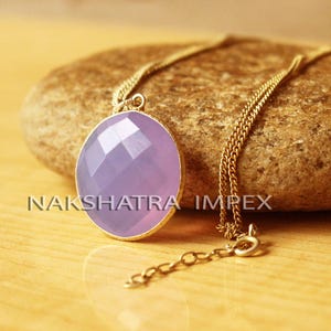 May include: A gold chain necklace with a lavender gemstone pendant. The pendant is round and faceted, and the chain is delicate.