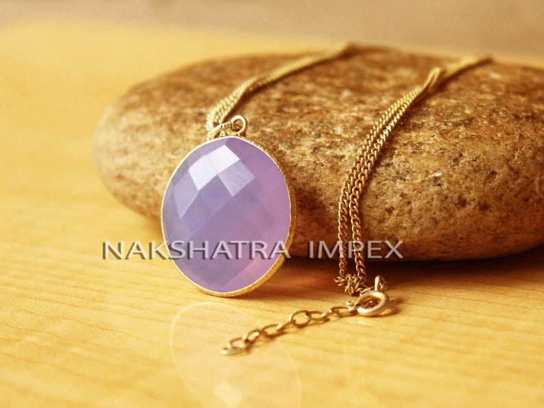 May include: A gold chain necklace with a lavender gemstone pendant. The pendant is round and faceted, and the chain is delicate.