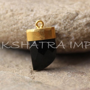 May include: A black onyx pendant with a gold-plated setting. The pendant is shaped like a tooth and has a faceted design.