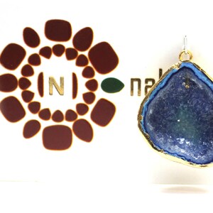 May include: A gold-plated pendant featuring a blue and green agate stone with a natural crystal formation. The pendant is on a white background with a logo that says "naktara".